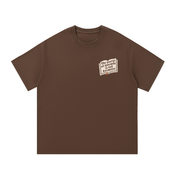 Mockup of a coffee brown cotton T-shirt with a small open book graphic reading 'the plural of anecdote is not evidence'