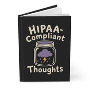 Angled mockup of a black hardcover journal with "HIPAA-Compliant Thoughts" and a jar with a purple storm cloud