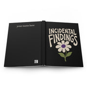 Black hardcover journal open flat showing 'Incidental Findings' front cover and back cover with 'your name here'