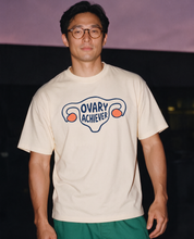 Man photographed with flash at night, wearing an apricot cotton T-shirt with the Ovary Achiever design.