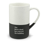 Mockup of a black and white speckled ceramic mug engraved "The black cloud has entered the building."