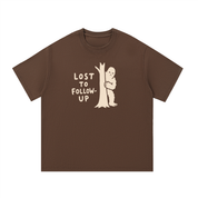Mockup of coffee cotton T-shirt with a Big Foot hiding behind a tree with the words "Lost to follow-up".