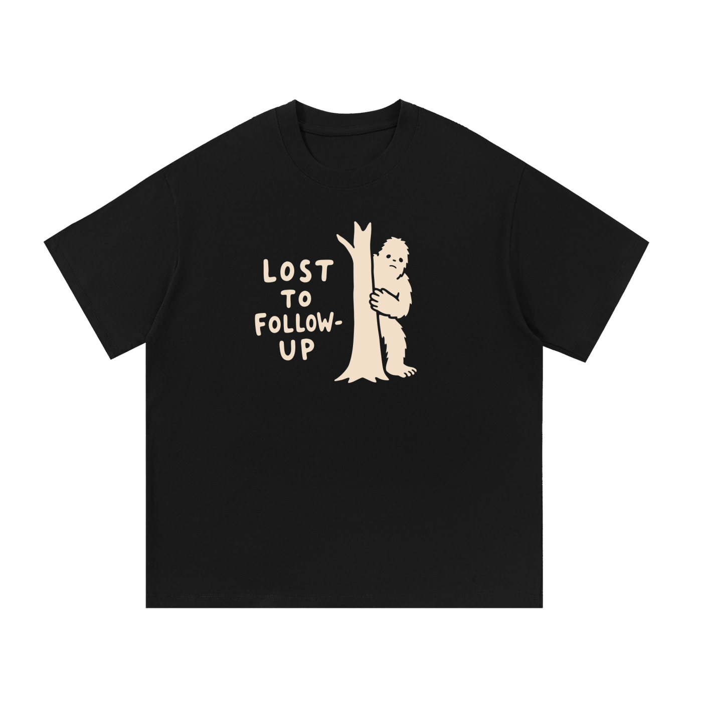 Mockup of black cotton T-shirt with a Big Foot hiding behind a tree with the words "Lost to follow-up".