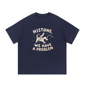 Mockup of a navy blue cotton T-shirt with a floating cartoon astronaut and the text 'Histone, We Have a Problem'