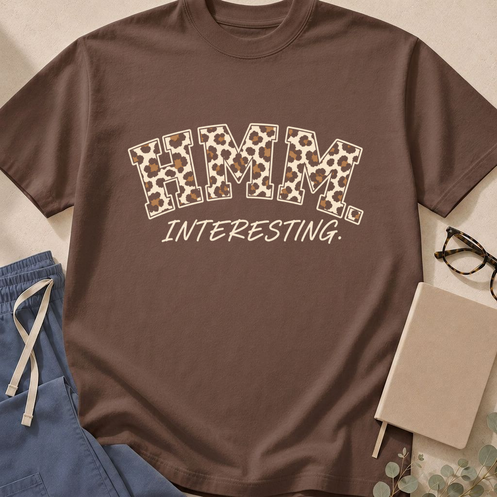 Garment-dyed unisex t-shirt printed with "Hmm, Interesting" — diagnostic humor tee for physicians, radiologists, and pathologists