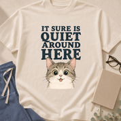 Garment-dyed unisex t-shirt printed with 'It Sure Is Quiet Around Here' — emergency department superstition humor tee featuring a cat design, for ED staff.