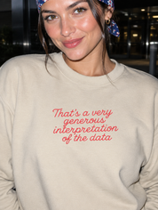 Model wearing the sand embroidered 'Generous Interpretation of the Data' sweatshirt, daytime editorial flash photo outside a hospital.