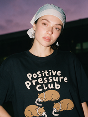 Woman photographed with flash at night, wearing a black cotton T-shirt with three capybaras wearing CPAP masks under the words 'Positive Pressure Club'.