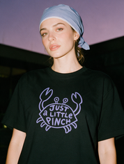 Woman photographed with flash at night, wearing a black cotton T-shirt with the 'Just a Little Pinch' design.
