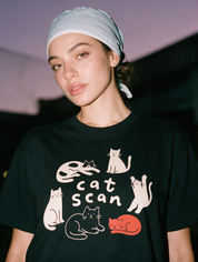 Woman photographed with flash at night, wearing a black cotton T-shirt with the 'Cat Scan' design.