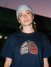 Woman photographed with flash at night, wearing a navy blue cotton T-shirt with the 'Pulmonary Toilet' design.