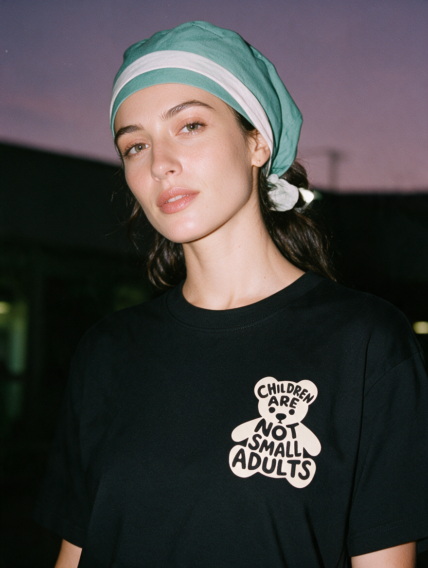 Woman photographed with flash at night wearing a black cotton T-shirt with 'Children Are Not Small Adults' design.