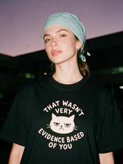 Woman photographed with flash at night wearing a black cotton T-shirt with 'That Wasn't Very Evidence Based Of You' design.