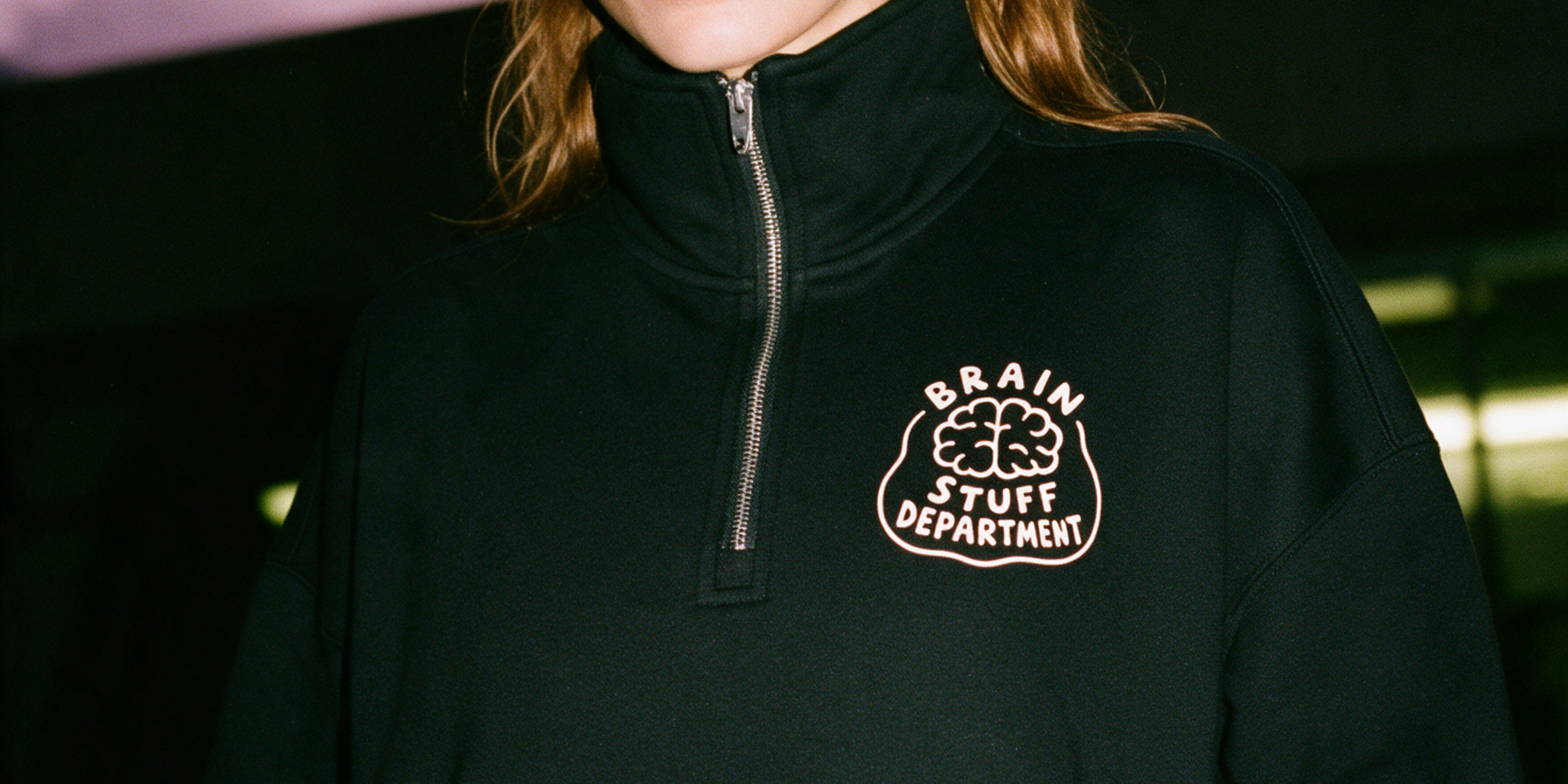 Physician wearing black 'Brain Stuff Department' quarter-zip sweatshirt, night editorial photo