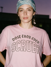 Woman photographed with flash at night, wearing a blue cotton T-shirt with gothic lettering reading "Dost thou even scrub?".