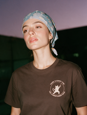 Woman photographed with flash at night, wearing a coffee cotton T-shirt with a cat holding a pin next to the words "There is always time for a monofilament exam".