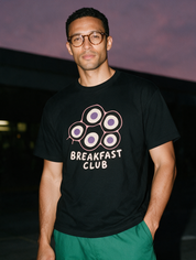 Man photographed with flash at night, wearing a black cotton T-shirt with hand-drawn eyeballs and the words 'Breakfast Club.'