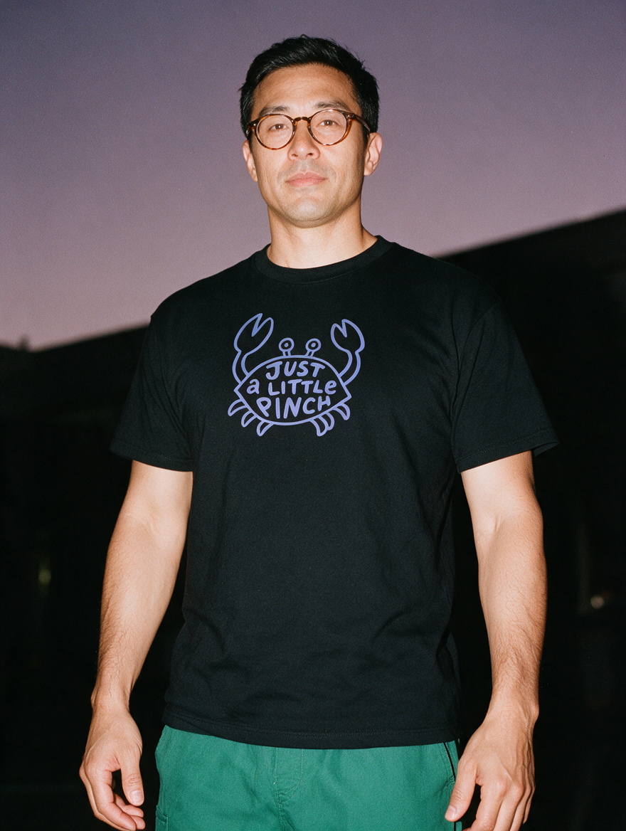 Man photographed with flash at night, wearing a black cotton T-shirt with the Just a Little Pinch design.