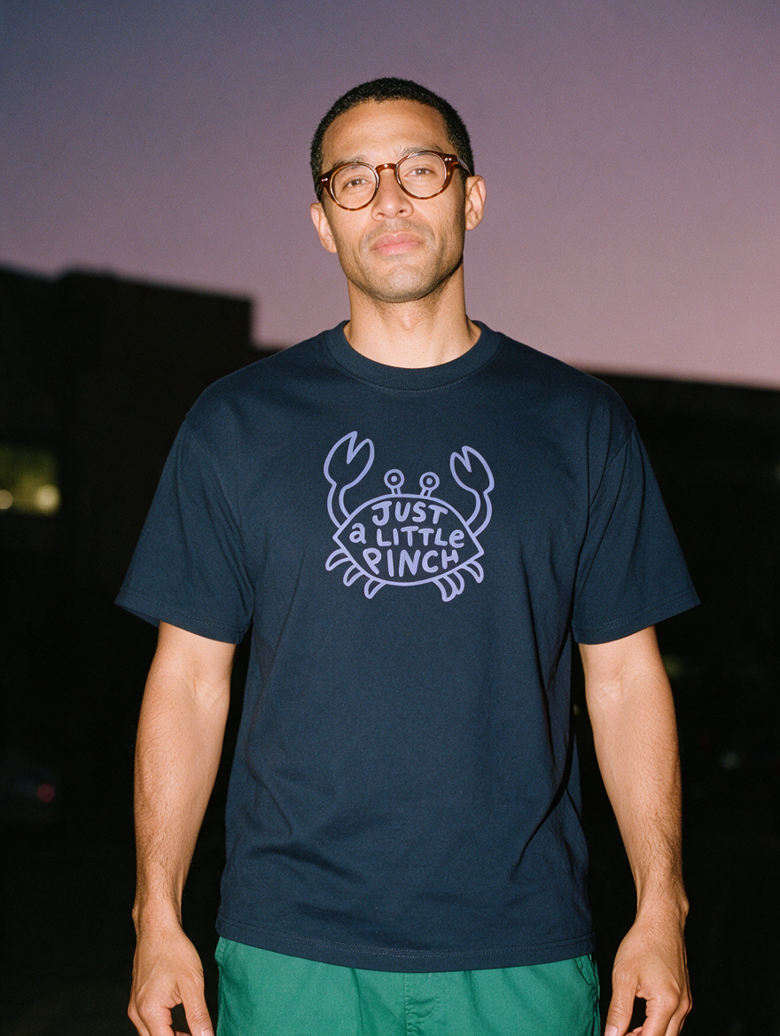 Man photographed with flash at night, wearing a navy blue cotton T-shirt with the Just a Little Pinch design.