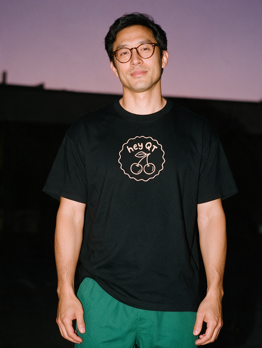 Man photographed with flash at night, wearing a black cotton T-shirt with the Hey QT design.