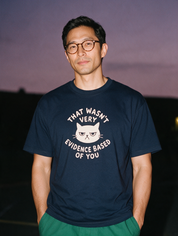 Man photographed with flash at night, wearing a navy blue cotton T-shirt with the That Wasn't Very Evidence Based of You design.