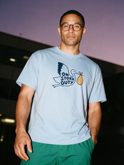 Man photographed with flash at night, wearing a blue cotton T-shirt with the On Stork Duty design.
