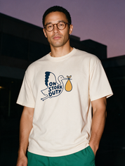 Man photographed with flash at night, wearing an apricot cotton T-shirt with the On Stork Duty design.