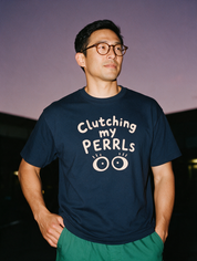 Man photographed with flash at night, wearing a navy blue cotton T-shirt with the Clutching My PERRLs design.