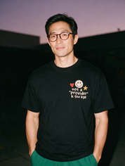 Man photographed with flash at night, wearing a black cotton T-shirt with the Not a Provider, K Thx Bye design.
