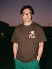 Man photographed with flash at night, wearing a coffee cotton T-shirt with the Not a Provider, K Thx Bye design.