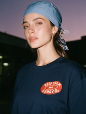 Woman photographed with flash at night, wearing a navy blue cotton T-shirt with a small red oval graphic reading 'Keep Calm and Carry O2'